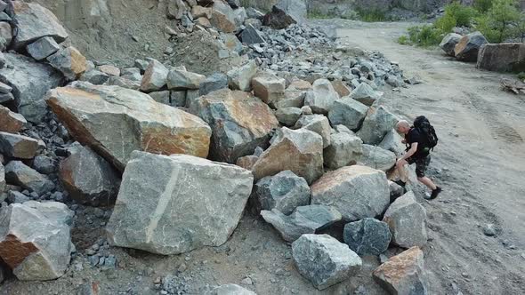 Active tourist climbing on a big pile of stones in the mountainous area.