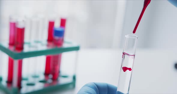 Scientist with Pipette Analyzes Red Colored Liquid To Extract the DNA