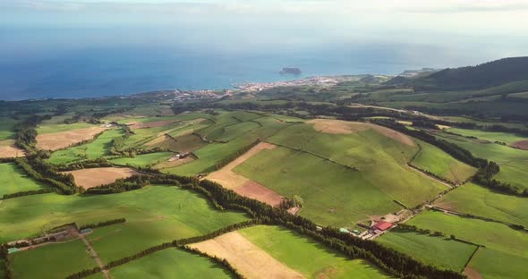 Aerial drone footage of the green agricultural fields and hills with sea views in Azores volcanic is