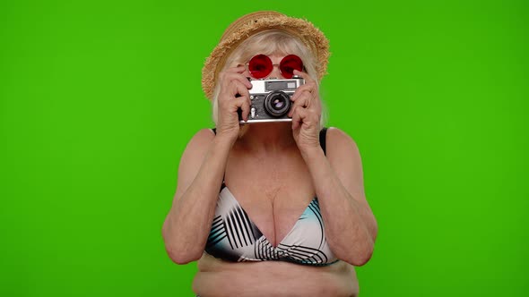 Senior Woman Tourist Photographer in Swimsuit Taking Photos on Retro Camera Smiling on Chroma Key