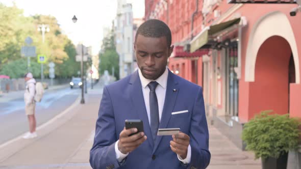 Excited African Businessman Shopping Online While Walking Outdoor