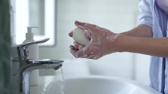 Beautiful, smiling blonde washes her hands thoroughly with soap and water