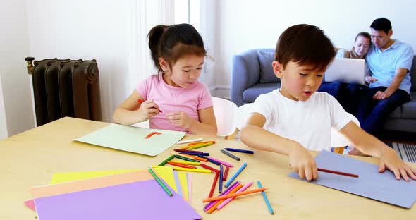 Children doing homework while parents relaxing on sofa