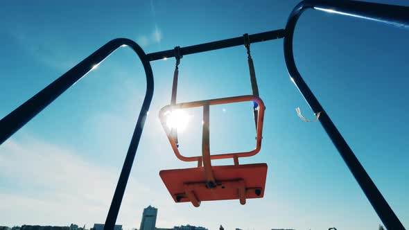 Sunlit Swings Are Swaying with Nobody on Them