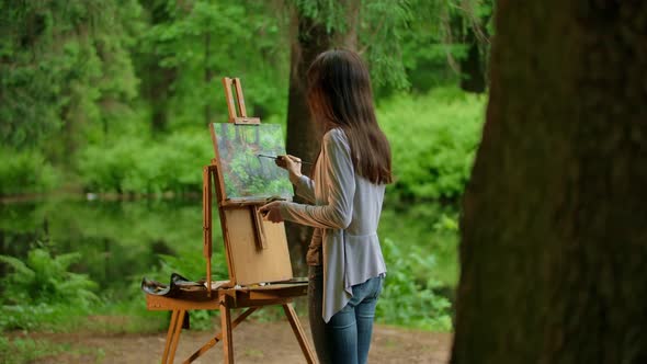 Rear View of a Young Artist Woman Painting a Landscape