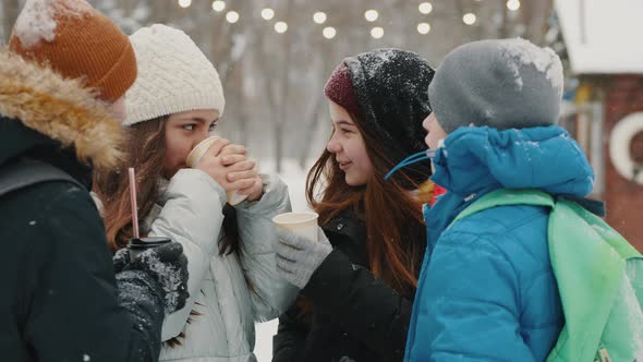 Smiling Teenagers Spend Time Together in Snowy Weather Drinking Warm Drinks