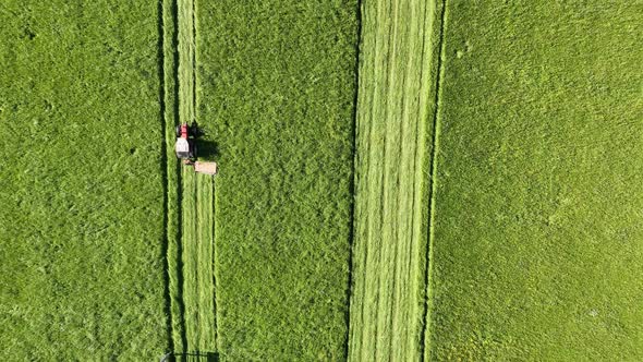 Aerial view of a tractor mowing a green fresh grass