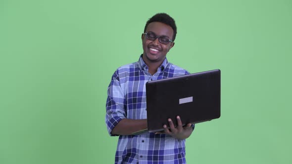 Happy Young African Hipster Man Thinking While Using Laptop