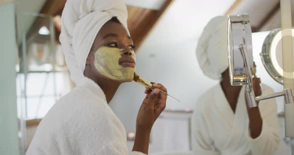 African american attractive woman applying face mask in bathroom