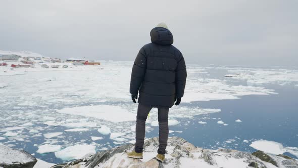 Man In Winter Coat Looking Over Frozen Coastline Of Ilulissat