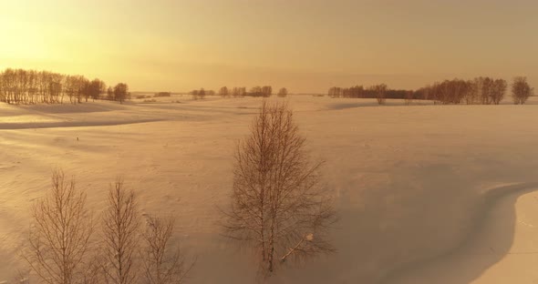 Aerial View of Cold Arctic Field Landscape Trees with Frost Snow Ice River and Sun Rays Over Horizon