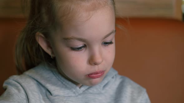 Little Girl Eats Dessert with Fresh Strawberries and Drinks Tea