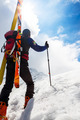 Ski mountaineer walking up along a steep snowy ridge with the skis in the backpack. - PhotoDune Item for Sale