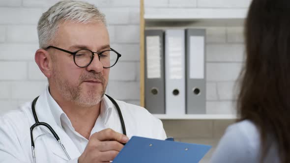 Male Doctor Talking With Sick Female Patient In Clinic