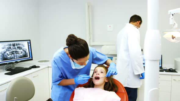 Dentist examining a young patient with tools