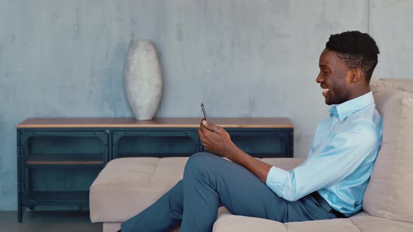 Smiling attractive businessman communicating by videoconference while sitting in lounge