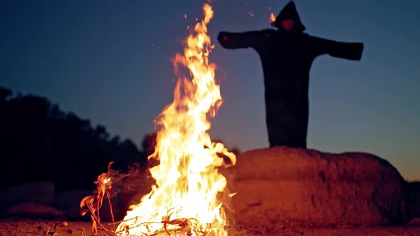 Terrible witch in the forest. Witch raising hand up near fire in forest