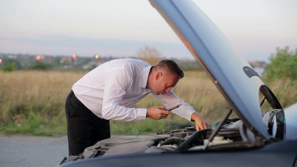 Young Businessman Waving for Help By Broken Down Car