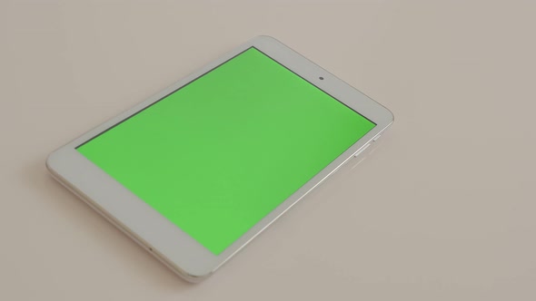 Silver tablet-pc with green screen display slow panning on white background 4K 2160p UltraHD footage