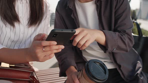 Two Women Scrolling on Smartphone Outdoors