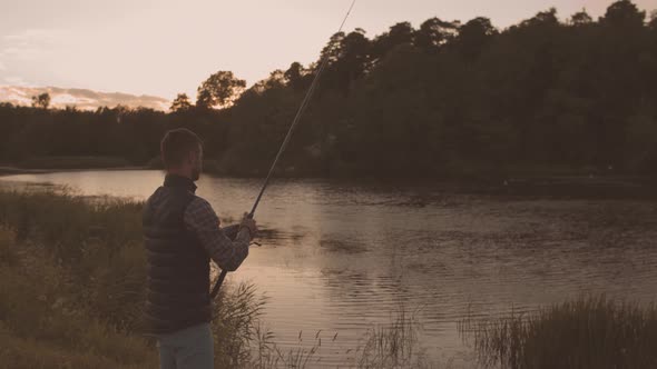 Fisherman with a spinning rod catching fish on a river.