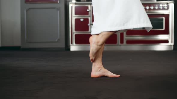 Cropped Shot of Barefoot Man in Bathrobe Walking in Modern Kitchen