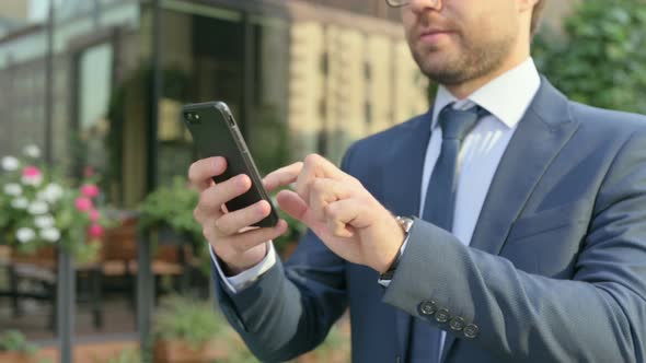 Hands Close up of Businessman using Smartphone while Walking in Street