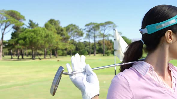 Golfer carrying golf club over shoulder while standing on the golf course