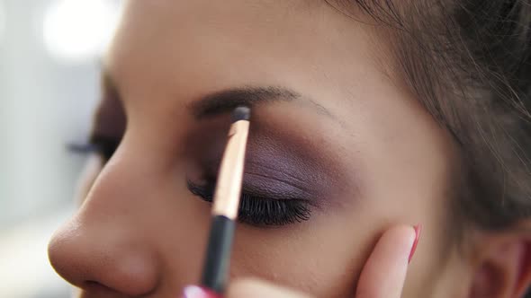 Closeup View of the Makeup Artist's Hands Correcting Eyebrows Using Special Brush