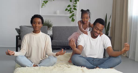 Mindful Father Dad and Mother Mom Meditating Sitting on Floor While Active Energetic Child Daughter