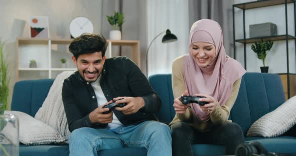 Guy Celebrating Victory in Video Game while His Arabic Girlfriend in Hijab