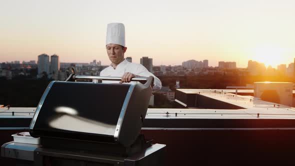 A professional Chef prepares a barbecue on the roof of a skyscraper. An expensive restaurant