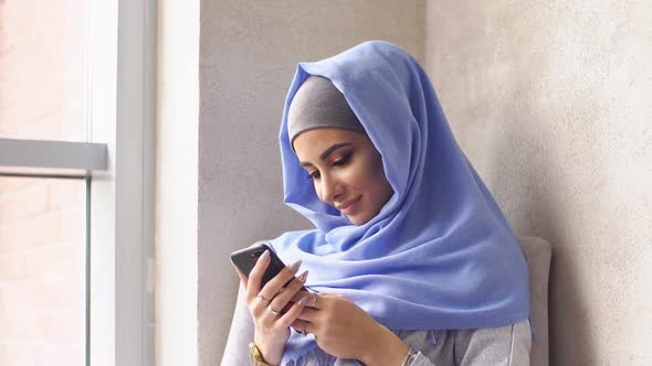 Young Muslim Girl in Hijab Sends Message From Smartphone