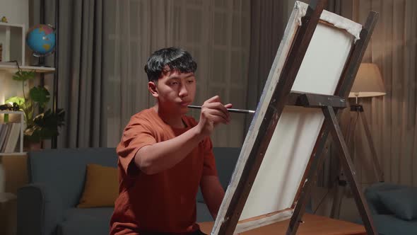 Asian Artist Boy Holding Paintbrush Mixed Colour And Painting On The Canvas