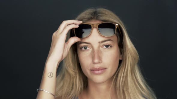 Young woman lifting up sunglasses and smiling at camera