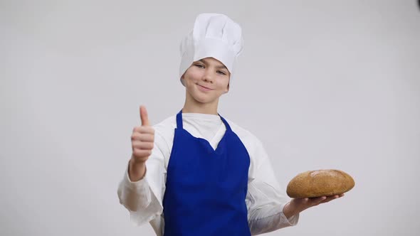 Proud Little Baker Holding Freshlybaked Bread Showing Thumb Up Smiling Looking at Camera