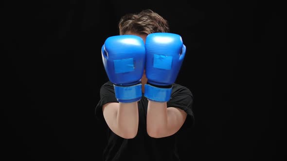 Female Hands in Blue Boxing Gloves Opening Face of Serious Young Brunette Woman Looking at Camera