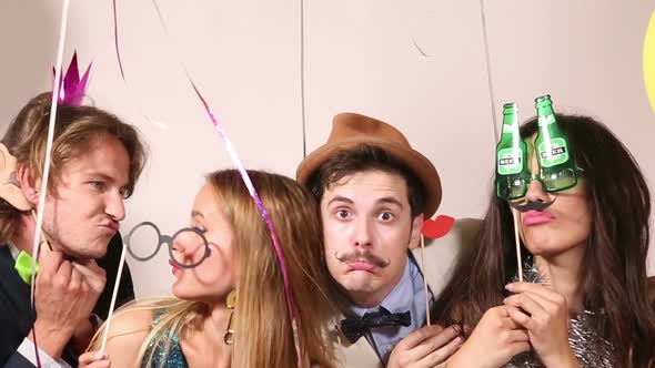 Funny couples playing with props in party photo booth