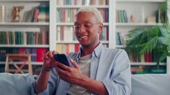 African Man Writes Message or Browses Social Networks on Modern Mobile Phone