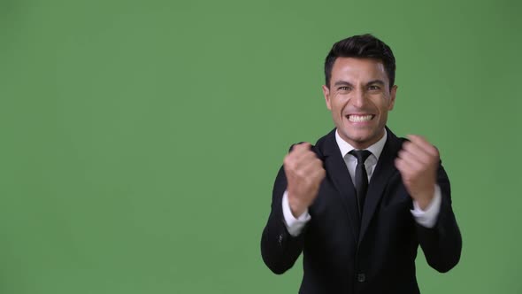 Young Handsome Hispanic Businessman Against Green Background