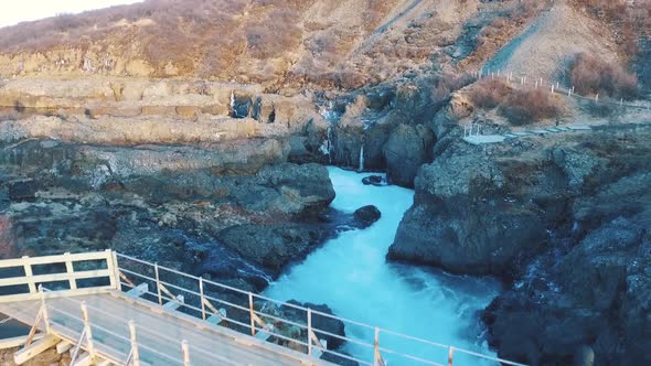 A scene of solitude shot with the drone over an icelandic river with a man on the bridge. Complexity