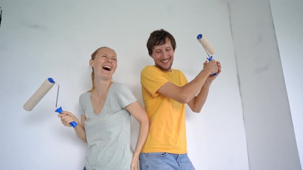 A Happy Man and Woman Paint the Wall Using a Roller Painter