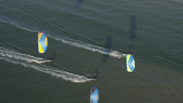 Kiteboarders being pulled fast across the sea water by power kites. Aerial , tracking view