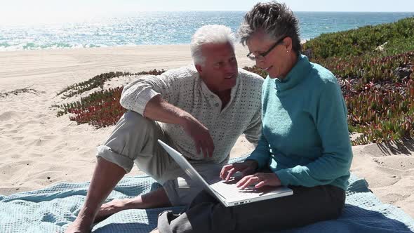 Couple looking at a laptop on the beach