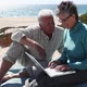 Couple looking at a laptop on the beach - VideoHive Item for Sale