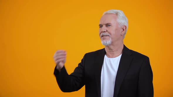 Happy Old Man in Suit Enjoying Pleasant Aroma Against Orange Background, Perfume