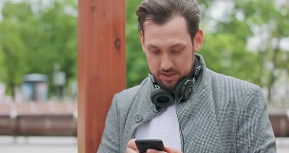 Face and Hands of Young Man with Mustaches and a Beard with Headphones on His Neck Stays on the