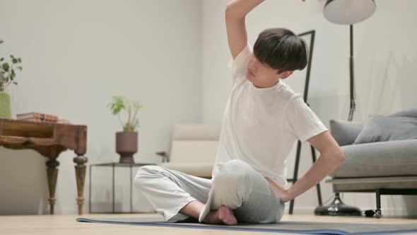 Asian Man Doing Stretches on Yoga Mat at Home