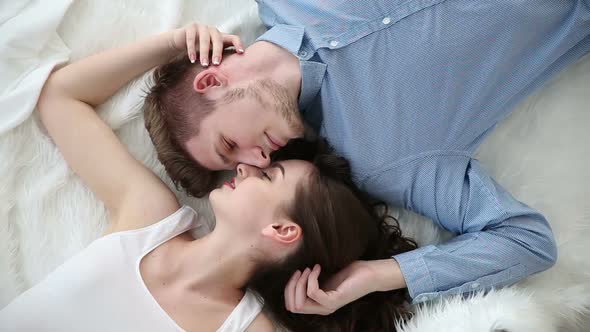 Young Loving Couple Lying on Bed at Home