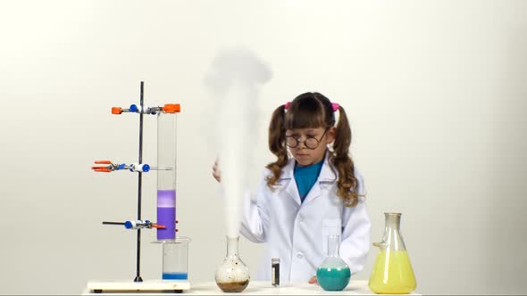 Little Girl Chemist with Two Ponytails in Uniform, Protective Glasses Has Successfully Tested the